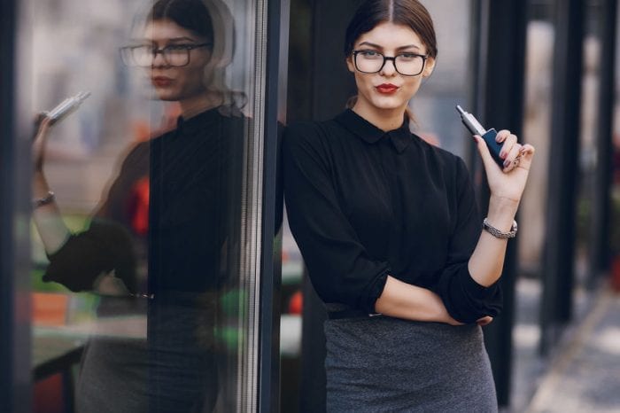 woman with a vape device leaning on glass